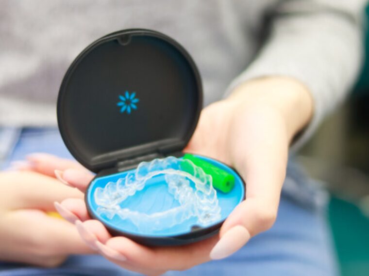 A clear Invisalign aligner in its case, held by a Park Lane Orthodontics patient