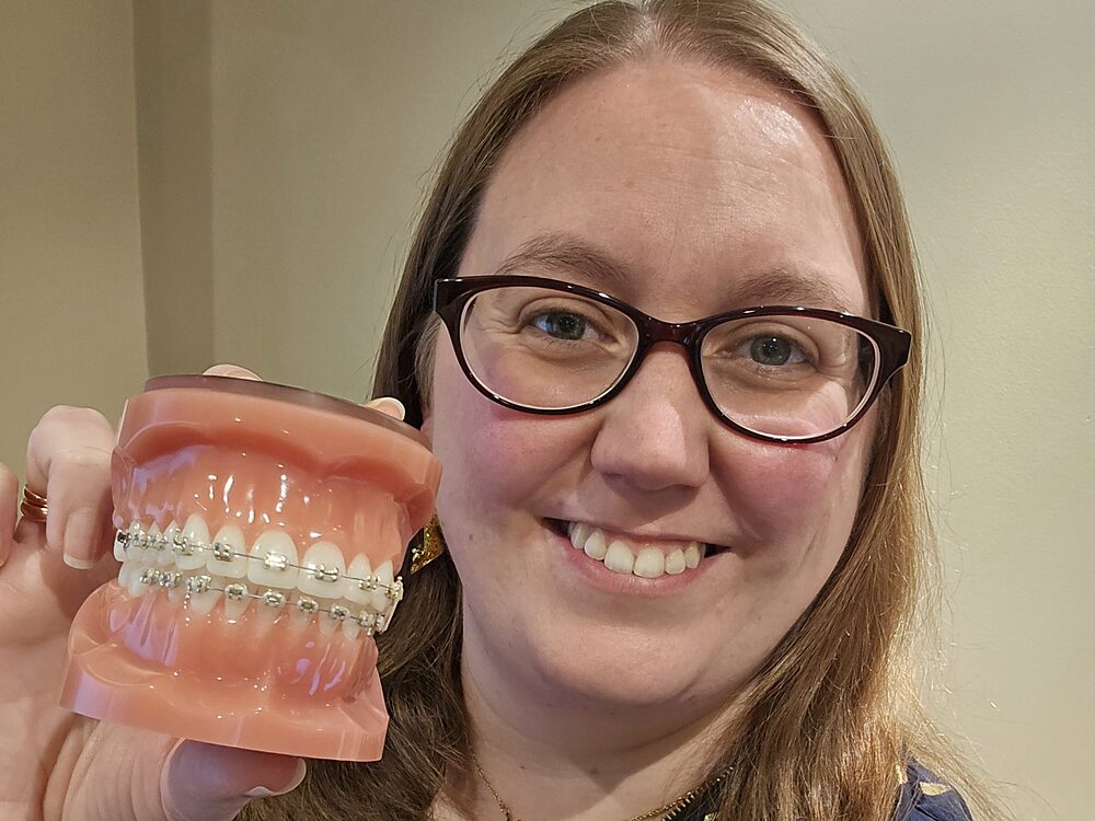 Park Lane Orthodontics team member holding a demonstration model of fixed braces