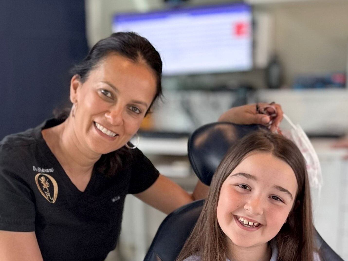 Dr Shivani Patel with a young patient holding a model of fixed braces at Park Lane Orthodontics