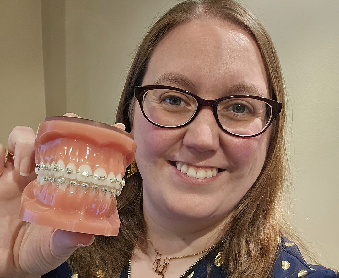 Park Lane Orthodontics team member holding a demonstration model of fixed braces