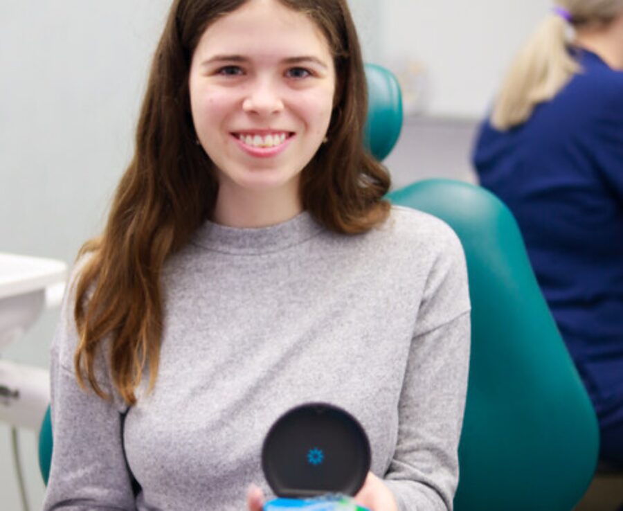 Park Lane Orthodontics patient smiling in the treatment chair holding her clear aligner case